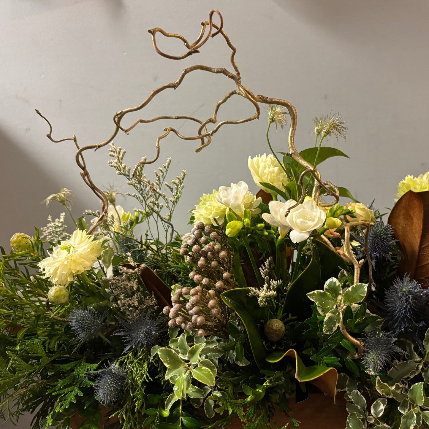 Floral arrangement with greenery, white flowers, and decorative elements on a neutral background