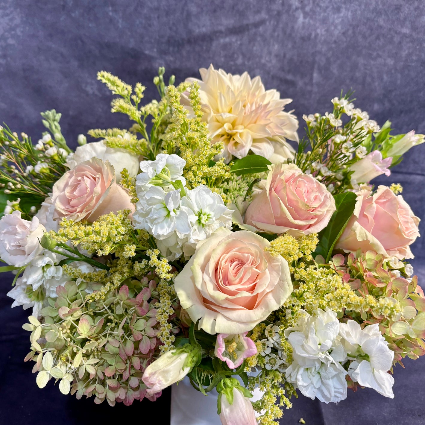 Bouquet of pink and white flowers with greenery on a dark background